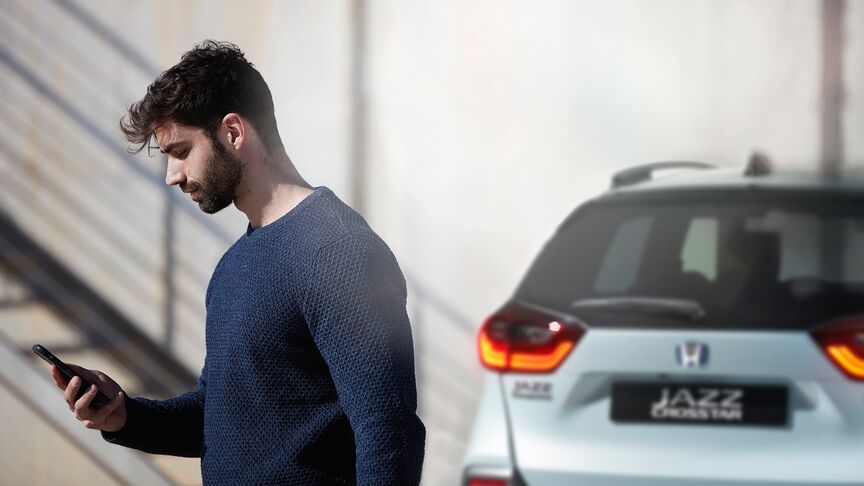 Dáma stojaca vedľa bieleho vozidla Honda e používajúca aplikáciu My Honda Plus