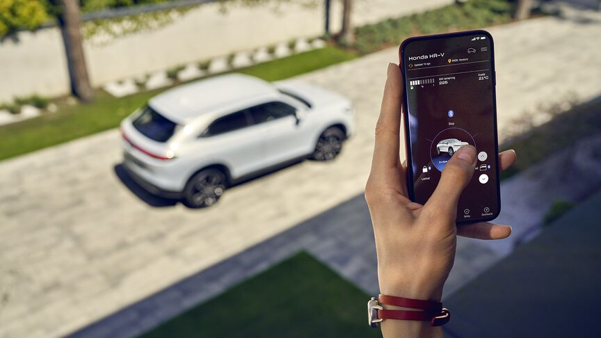 Dáma stojaca vedľa bieleho vozidla Honda e používajúca aplikáciu My Honda Plus