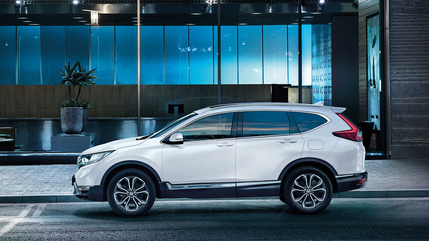 Trojštvrťový záber spredu na model CR-V pri jazde mestom.