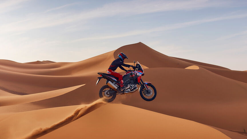 Model Africa Twin v teréne s jazdcom v piesočných dunách