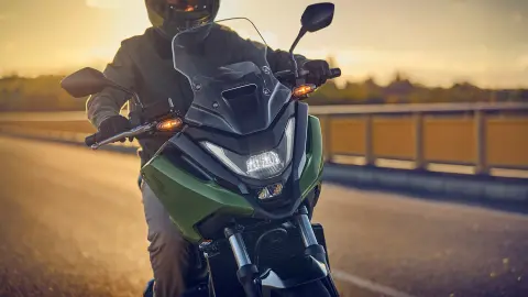 Záber spredu na figuranta pri jazde na motocykli NC750X na ceste.