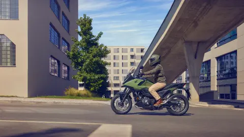 Bočný záber na figuranta pri jazde na motocykli NC750X v meste.