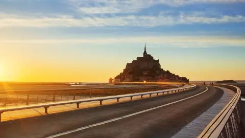 Cesta na Mont-Saint-Michel pri západe slnka, Normandia, Francúzsko.