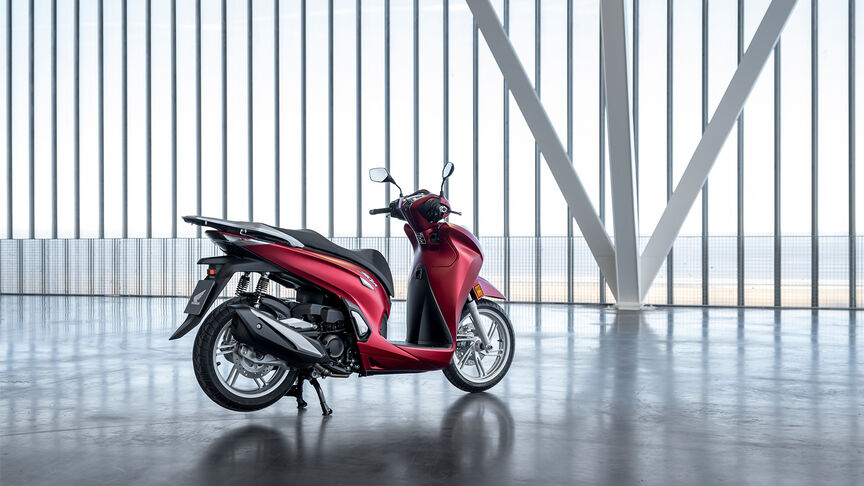 Honda SH350i, trojštvrťový predný záber z pravej strany, s jazdcom, na ceste, červený motocykel