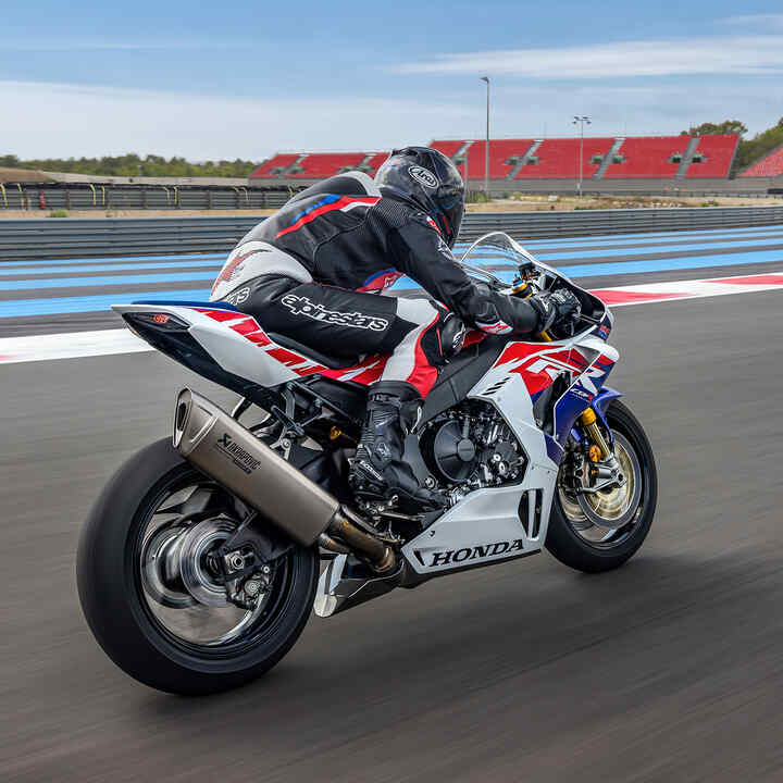 Zadný trojštvrťový pohľad na motocykel Honda CBR1000RR-R Fireblade s jazdcom na pretekárskej trati