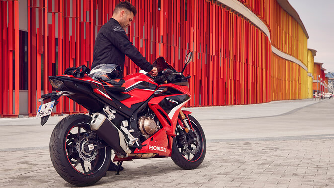 Trojštvrťový záber zozadu na stojaci model Honda CBR500R s jazdcom